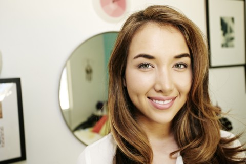 Hispanic woman smiling near mirror
