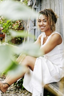 Smiling Mixed Race woman drinking coffee in garden