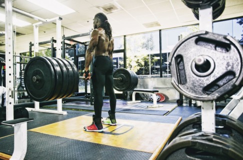 Black man lifting barbell in gymnasium