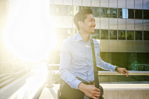 Smiling Mixed Race businessman walking outdoors on sunny day