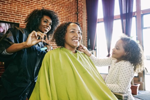 Smiling hairdresser and customers in hair salon