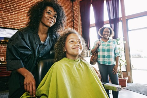Smiling hairdresser and customers in hair salon
