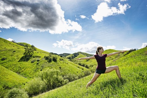 Caucasian woman doing yoga on hill