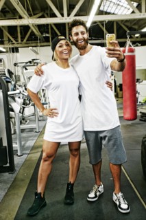 Mixed Race man couple posing for cell phone selfie in gymnasium