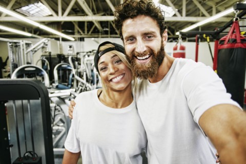 Mixed Race man couple posing for cell phone selfie in gymnasium