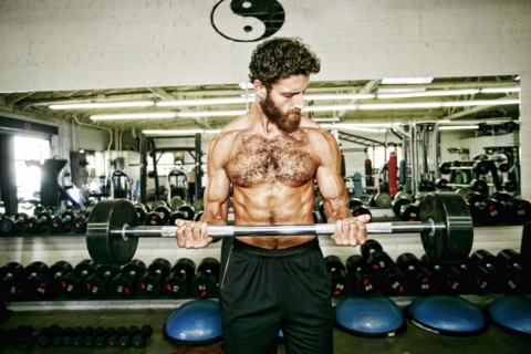 Mixed Race man lifting barbell in gymnasium