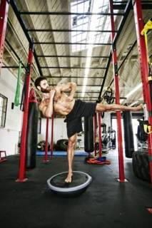 Mixed Race man standing on balance trainer in gymnasium
