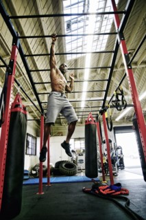 Black man hanging from bars in gymnasium