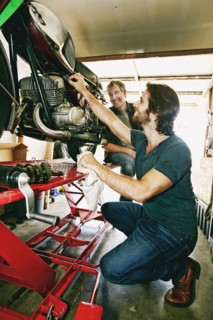 Caucasian father watching son repairing motorcycle in garage