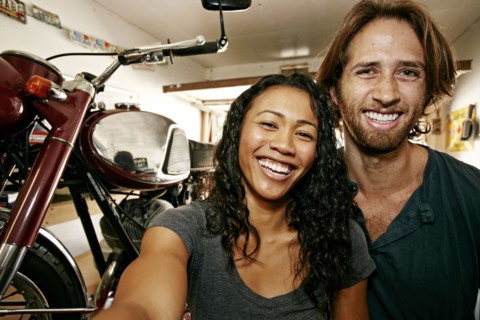 Man and woman posing for selfie with motorcycle in garage