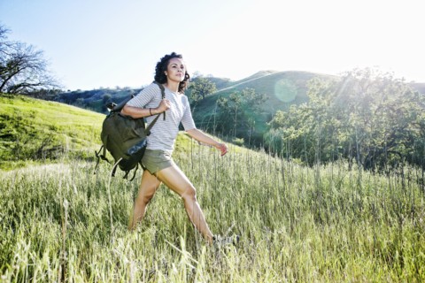 Smiling Mixed Race woman hiking on hill