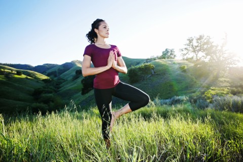 Mixed Race woman practicing yoga on hill