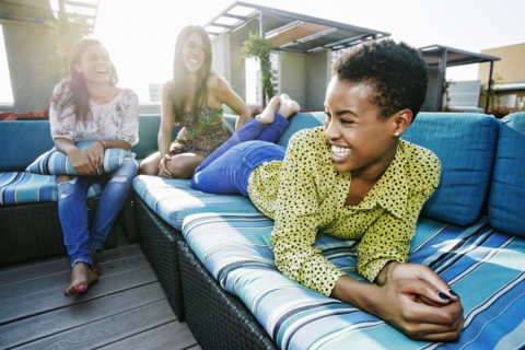 Friends laughing on rooftop sofa