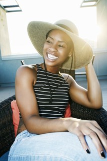 Black woman wearing sun hat on rooftop