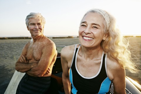 Older Caucasian couple leaning on convertible car at beach
