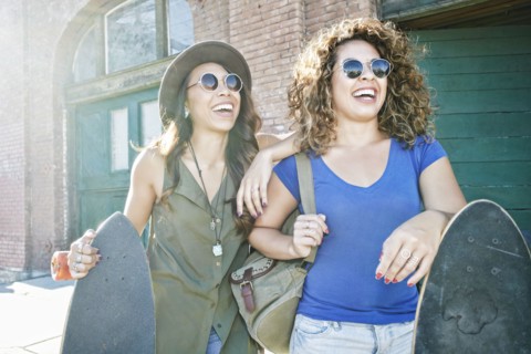 Mixed Race women holding skateboards in city
