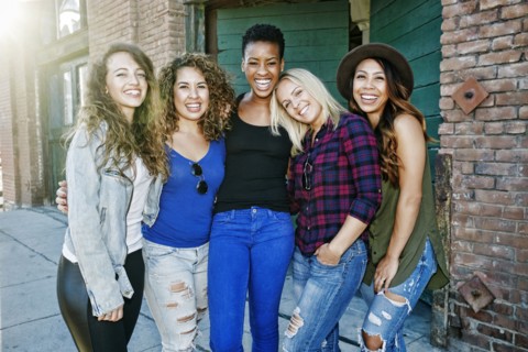 Women posing on sidewalk in city