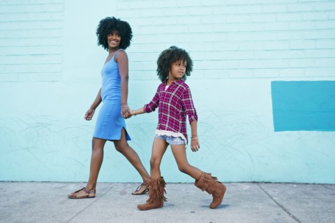 Smiling mother and daughter walking on sidewalk