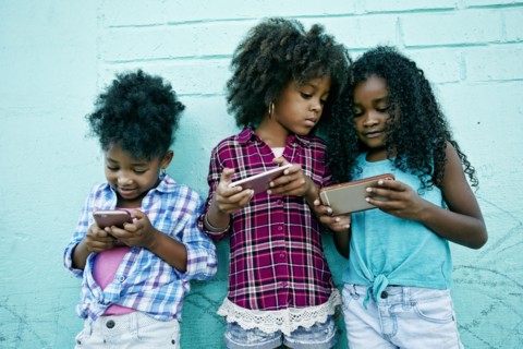 Girls leaning on wall texting on cell phones