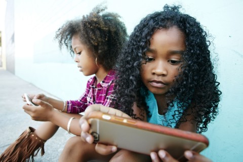 Girls sitting on sidewalk texting on cell phones