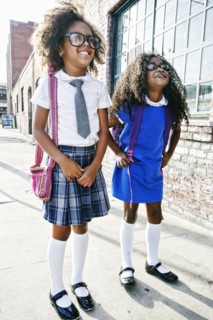 Smiling girls standing on sidewalk ready for school