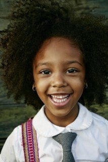 Portrait of smiling Mixed Race girl near wooden wall