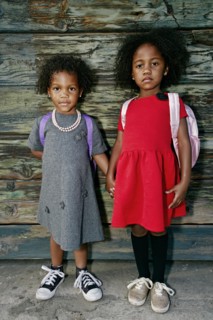 Portrait of serious girls standing near wooden wall