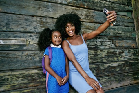Black mother and daughter posing for cell phone selfie