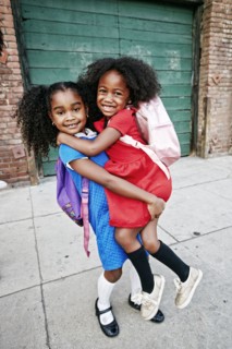 Portrait of smiling girl lifting friend on sidewalk
