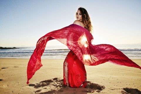 Caucasian belly dancer holding scarf on beach