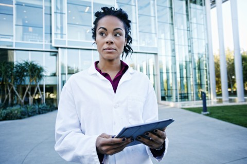Portrait of curious Mixed Race doctor holding digital tablet outdoors