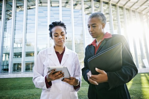 Doctor and administrator outdoors at hospital using digital tablet