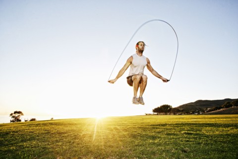 Caucasian man jumping rope in sunny field