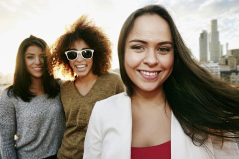 Portrait of smiling women on urban rooftop at sunset