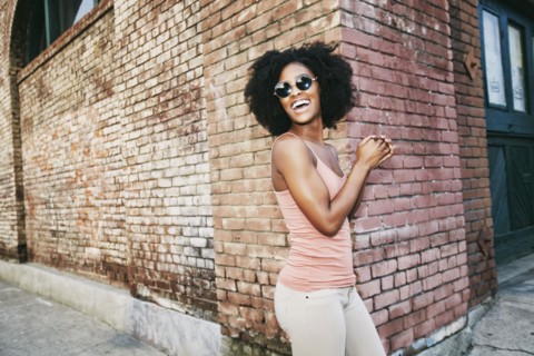 Laughing Black woman standing near corner of brick building