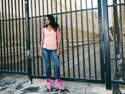 Black woman wearing roller skates near metal gate