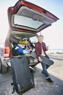 Caucasian man holding skateboard and texting on cell phone