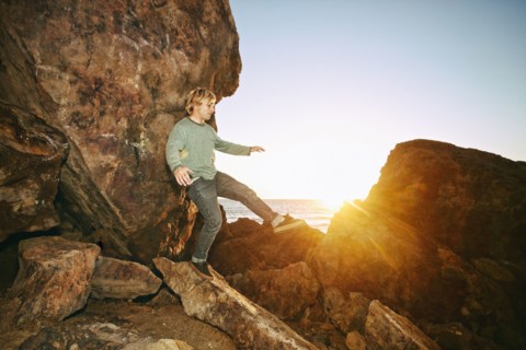 Caucasian man balancing on rocks at ocean