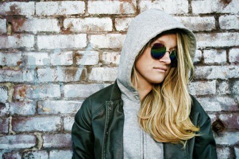 Caucasian woman wearing sunglasses near brick wall