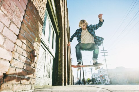 Caucasian man jumping on skateboard on urban sidewalk