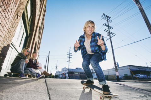 Women watching man skateboarding on urban sidewalk