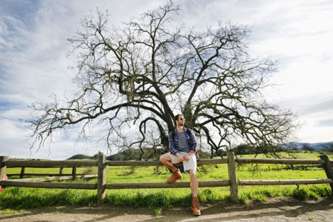 Caucasian man resting on wooden fence