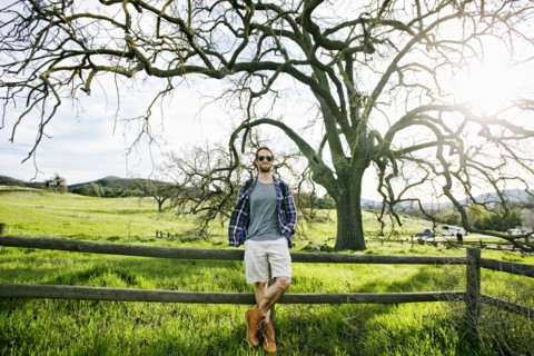 Caucasian man resting on wooden fence