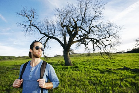 Caucasian man standing in field near tree