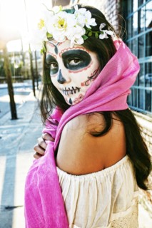 Mixed Race woman on sidewalk wearing scarf and skull face paint