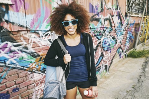 Hispanic woman standing near graffiti wall
