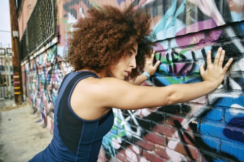 Hispanic woman leaning on graffiti wall