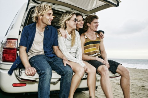 Caucasian friends sitting in car hatch at beach