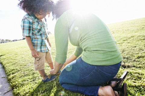 Mixed race mother tying shoe of son