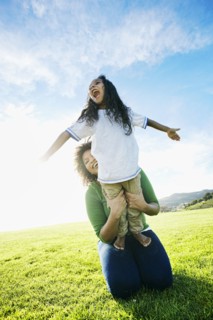 Mixed race mother holding daughter pretending to be airplane